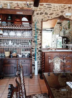 a kitchen with a table and a stone wall at Fogar de Insua in Touro