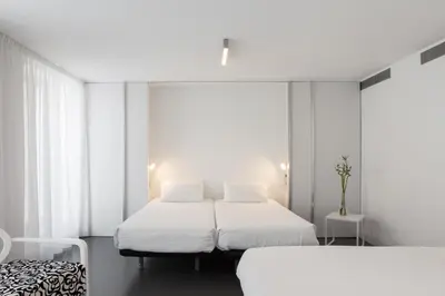 two beds in a room with white walls and windows at Moure Hotel in Santiago de Compostela