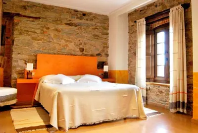 a bedroom with a large bed with a brick wall at La Lechería in Val de San Lorenzo