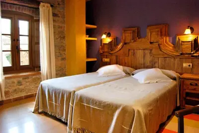 a bedroom with a large bed with a wooden headboard at La Lechería in Val de San Lorenzo