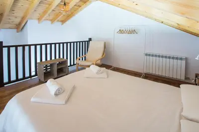 a room with a large white bed and a chair at Os Feleitos in Orellán