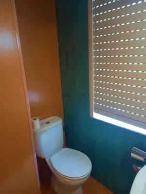 a bathroom with a white toilet and a window at Pension San Roque in Lugo