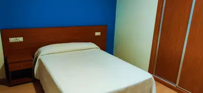 a bed in a room with a blue wall at Pension San Roque in Lugo