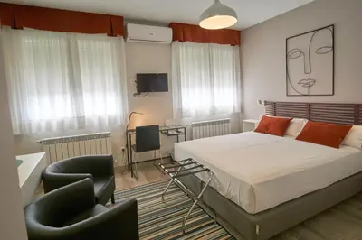 a bedroom with a bed and a desk and chairs at Apartamentos Los Arroyos in Ponferrada