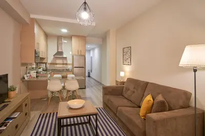 a living room with a couch and a kitchen at Apartamentos Los Arroyos in Ponferrada