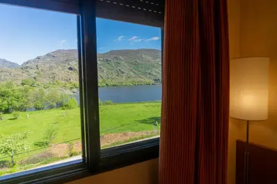a window with a view of a lake and mountains at Hotel Don Pepe Lago de Sanabria in Ribadelago