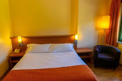 a hotel room with a bed and a chair at Hotel Don Pepe Lago de Sanabria in Ribadelago