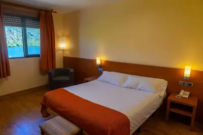 a hotel room with a bed and a chair at Hotel Don Pepe Lago de Sanabria in Ribadelago