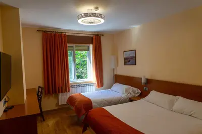 a hotel room with two beds and a window at Hotel Don Pepe Lago de Sanabria in Ribadelago
