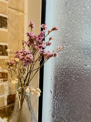 a vase with purple flowers in it next to a window at Hotel Don Pepe Lago de Sanabria in Ribadelago