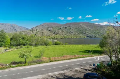 a road with a lake and mountains in the background at Hotel Don Pepe Lago de Sanabria in Ribadelago