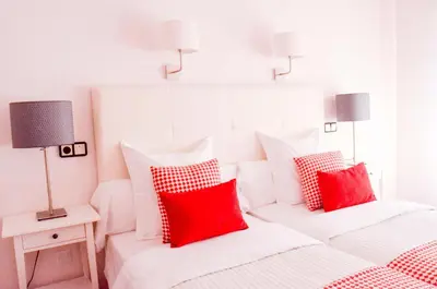 two beds with red and white pillows in a bedroom at Hostal Carlos V in Puebla de Sanabria