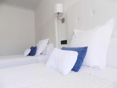 a bedroom with two white beds with blue pillows at Hostal Carlos V in Puebla de Sanabria