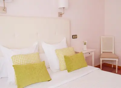 a bedroom with a white bed with yellow and white pillows at Hostal Carlos V in Puebla de Sanabria