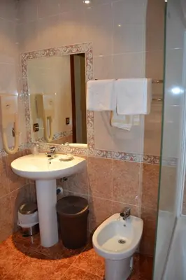 a bathroom with a sink and a toilet and a mirror at Hostal Carlos V in Puebla de Sanabria