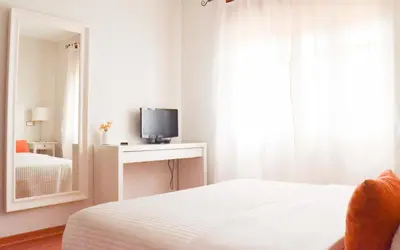 a bedroom with a bed and a mirror and a television at Hostal Carlos V in Puebla de Sanabria