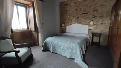 a bedroom with a bed and a chair and a window at Casa Dos Cregos in Bascuas