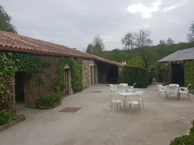 a patio with white chairs and tables and a building at Casa da Ponte in Ferreira