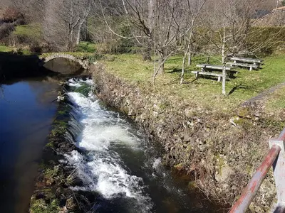 a river with a bridge and a picnic table at Casa da Ponte in Ferreira