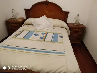a bed with a wooden headboard and two night stands at Secondary home in Lobios