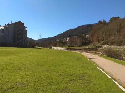 a grassy field next to a building and a road at Secondary home in Lobios
