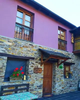 a building with red flowers in a window at La Cabana´l Cachican in Cangas del Narcea