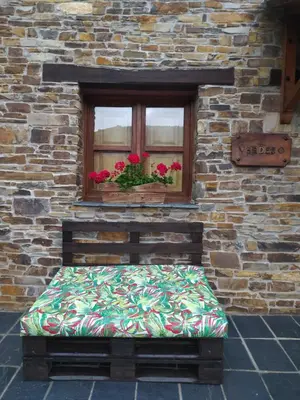 a bed sitting in front of a window with flowers at La Cabana´l Cachican in Cangas del Narcea