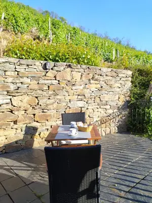 a table with two chairs and a stone wall at La Cabana´l Cachican in Cangas del Narcea