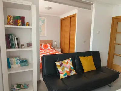 a living room with a black couch and a bed at Casa Riquiña in Santiago de Compostela