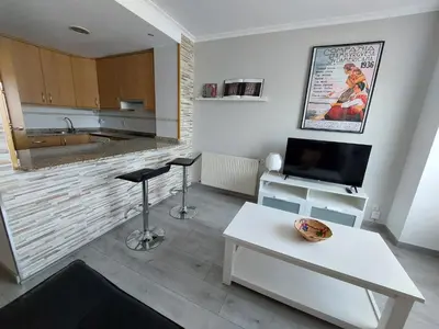 a living room with a table and a tv and a kitchen at Casa Riquiña in Santiago de Compostela