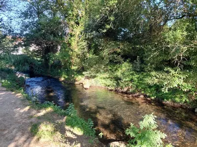 a river next to a road and some trees at Casa Riquiña in Santiago de Compostela