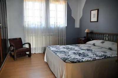 a bedroom with a bed and a chair and a window at Hotel Rural Molino del Arriero in Luyego de Somoza