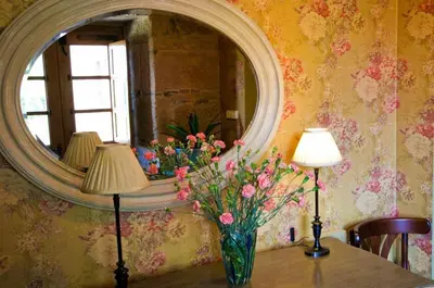 a vase of flowers on a table with a mirror at A Casa da Torre Branca in Santiago de Compostela