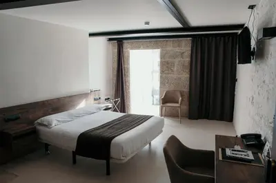 a bedroom with a bed and a desk and a chair at Via Aetcal Hotel & Wellness in Santiago de Compostela