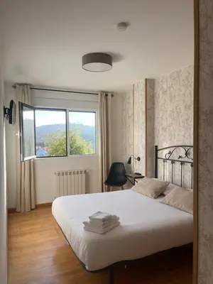 a bedroom with a large white bed with a window at Pension 23-Vinte e Tres in O Pedrouzo