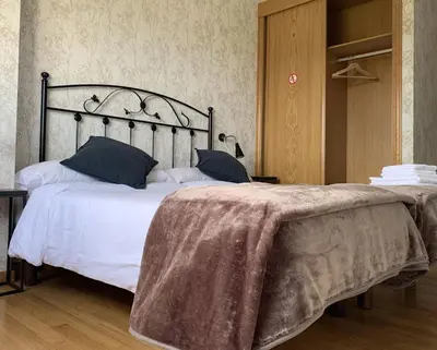 a bedroom with a large bed with white sheets and blue pillows at Pension 23-Vinte e Tres in O Pedrouzo