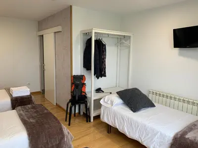 a bedroom with two beds and a backpack on a chair at Pension 23-Vinte e Tres in O Pedrouzo
