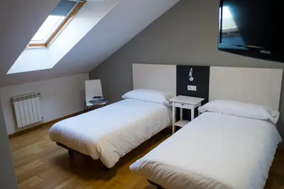 two beds in a room with a attic at Pension 23-Vinte e Tres in O Pedrouzo