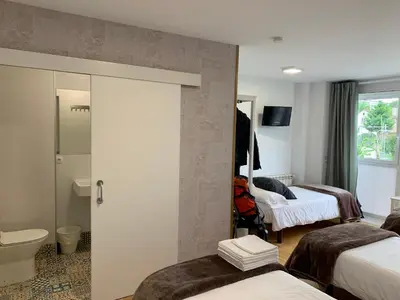 a hotel room with two beds and a bathroom at Pension 23-Vinte e Tres in O Pedrouzo