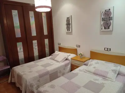 a bedroom with two beds and a chandelier at O Lar de Sara in Pontevedra