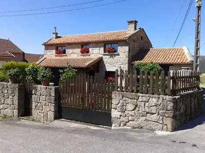 a house with a wooden gate and a stone fence at O Lar de Sara in Pontevedra