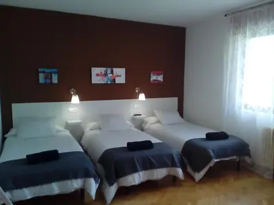 a bedroom with two beds with blue covers and a window at Casa Ribeira Sacra Portomarin in Portomarin