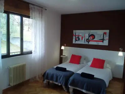 a bedroom with two beds with red and blue pillows at Casa Ribeira Sacra Portomarin in Portomarin