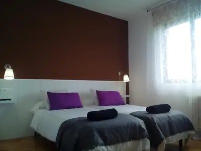 a bedroom with a large bed with purple pillows at Casa Ribeira Sacra Portomarin in Portomarin