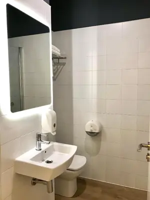 a bathroom with a sink and a toilet and a mirror at Albergue O Burgo in O Pedrouzo