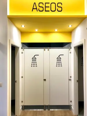 a row of exit doors with aces signs on them at Albergue O Burgo in O Pedrouzo