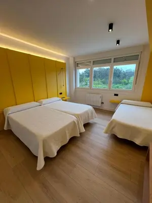 two beds in a room with two windows at Albergue O Burgo in O Pedrouzo