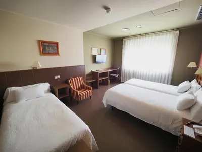 a hotel room with two beds and a chair at Hotel EO in Ribadeo