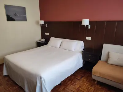 a hotel room with a large bed and a chair at Hotel EO in Ribadeo