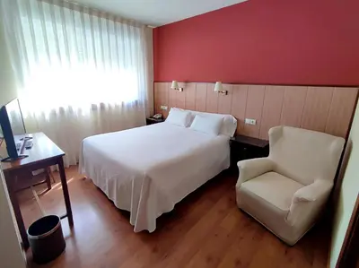 a hotel room with a bed and a chair at Hotel EO in Ribadeo
